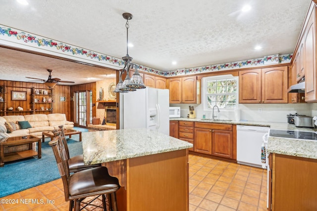 kitchen featuring decorative light fixtures, a center island, a textured ceiling, sink, and white appliances