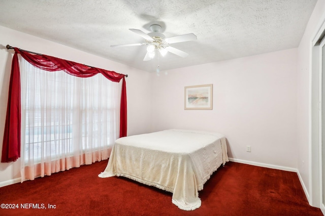 bedroom featuring a textured ceiling, dark colored carpet, and ceiling fan