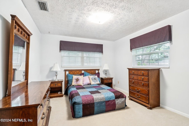 bedroom featuring a textured ceiling and light carpet