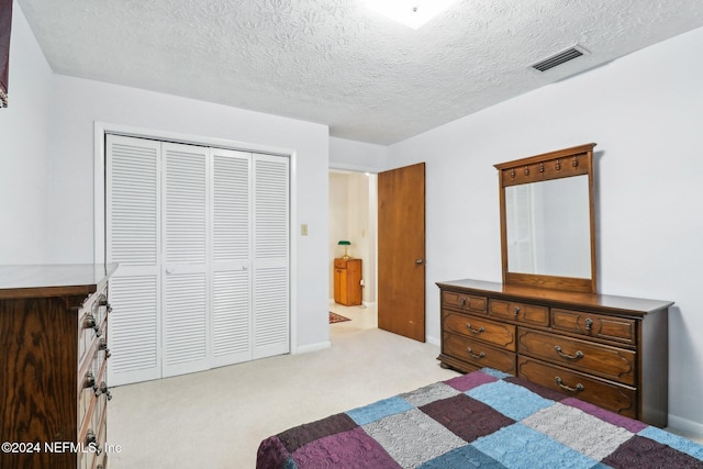 bedroom featuring a closet, a textured ceiling, and light colored carpet