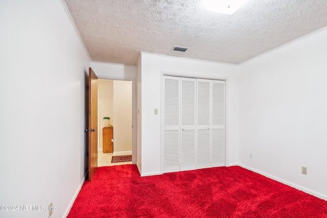 unfurnished bedroom featuring a closet, carpet, a textured ceiling, and crown molding