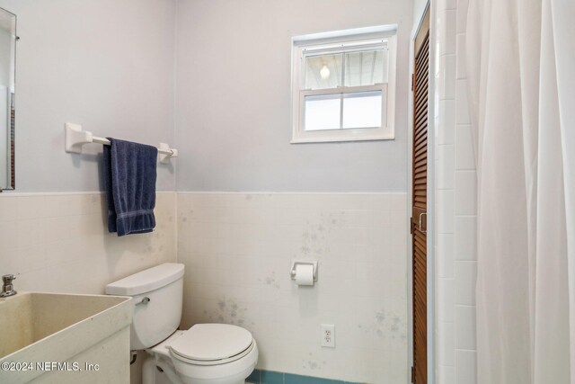 bathroom featuring tile walls, sink, and toilet