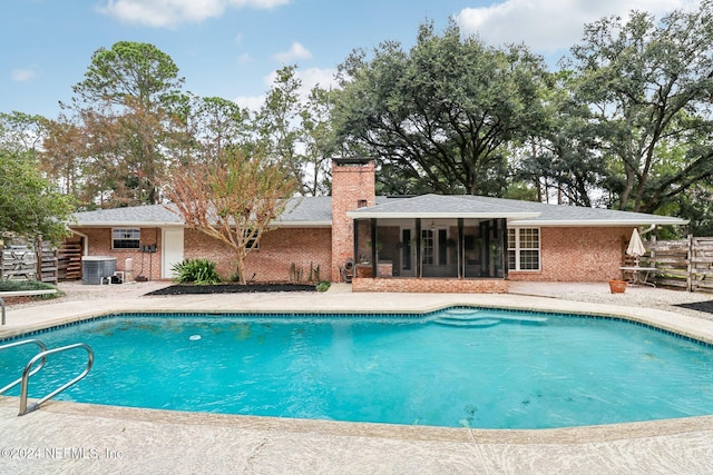 view of swimming pool with cooling unit, a patio, and a sunroom