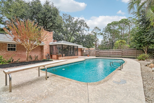 view of swimming pool with a sunroom and a patio area