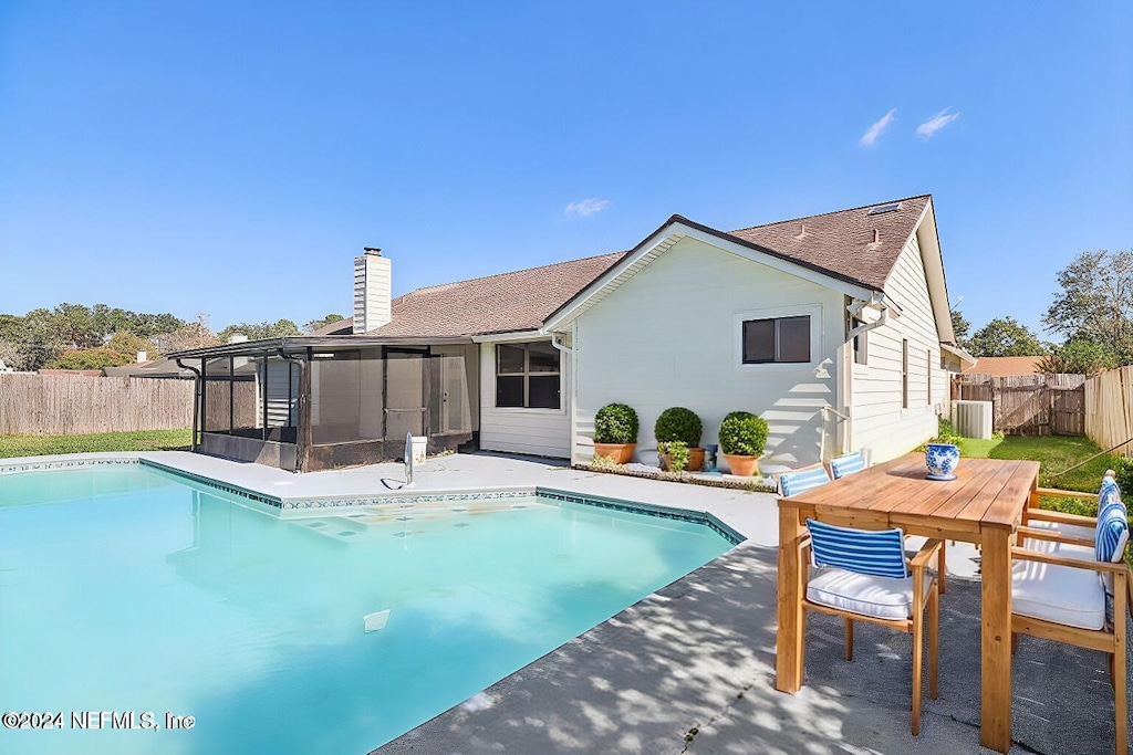 back of property with a fenced in pool and a sunroom