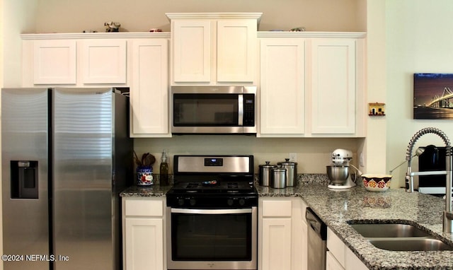 kitchen with appliances with stainless steel finishes, white cabinets, and a sink