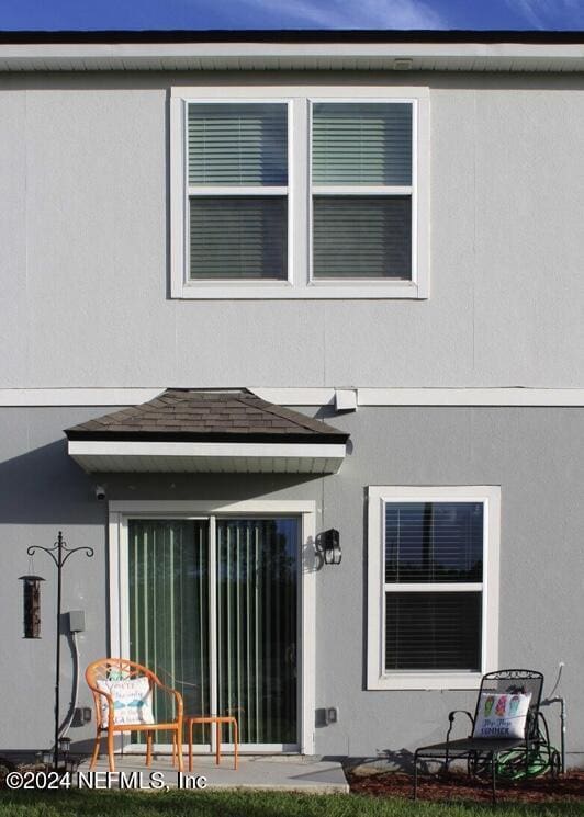 rear view of house featuring stucco siding