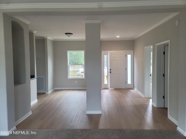 foyer entrance featuring ornamental molding, a textured ceiling, and light wood-type flooring