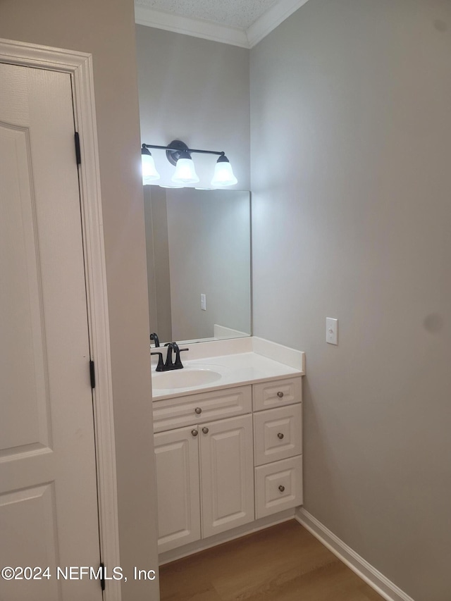 bathroom featuring vanity, crown molding, wood-type flooring, and a textured ceiling