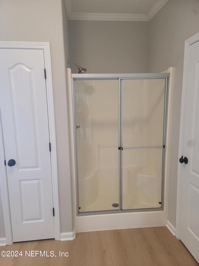 bathroom with crown molding, hardwood / wood-style floors, and walk in shower