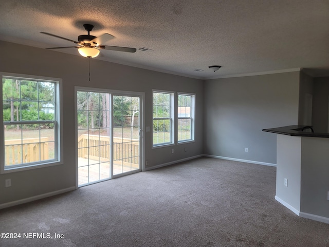 unfurnished living room with ornamental molding, carpet floors, a textured ceiling, and ceiling fan