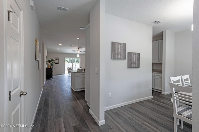 hallway featuring a textured ceiling and dark hardwood / wood-style flooring