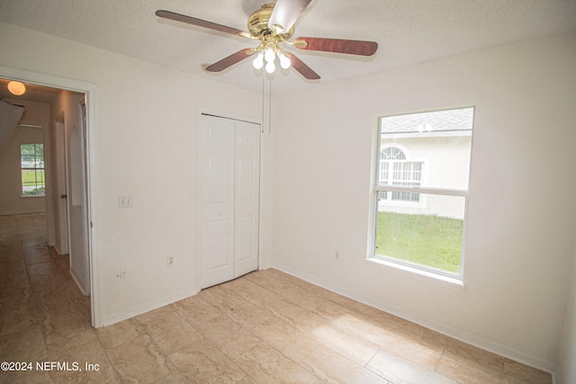 unfurnished bedroom featuring a closet, a textured ceiling, and ceiling fan