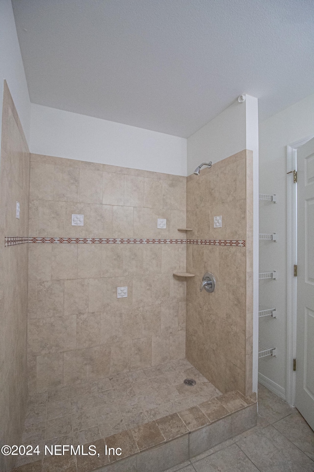 bathroom with a tile shower and tile patterned flooring