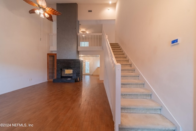 staircase with a high ceiling, wood-type flooring, and ceiling fan