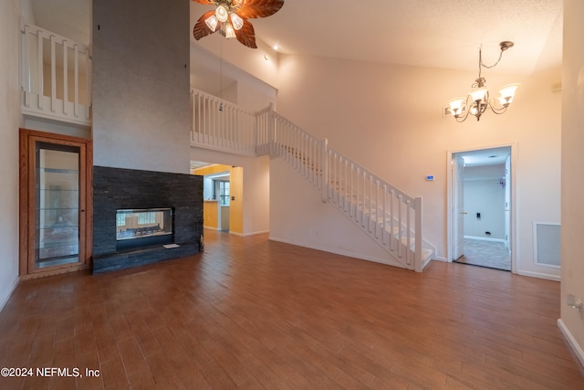 unfurnished living room with hardwood / wood-style flooring, high vaulted ceiling, a multi sided fireplace, and ceiling fan with notable chandelier