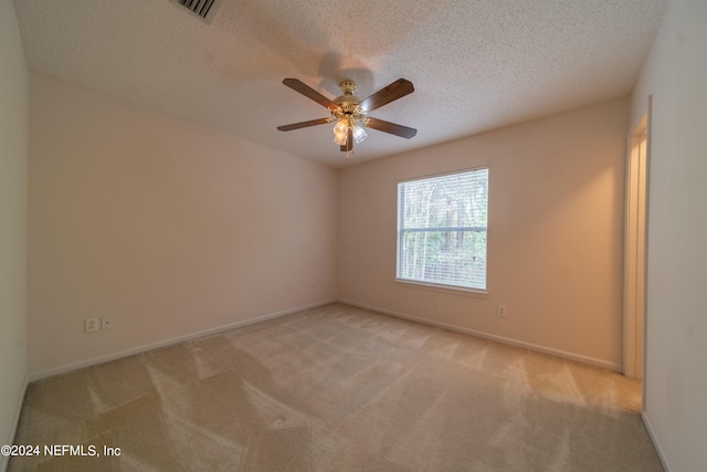 spare room featuring light carpet, a textured ceiling, and ceiling fan