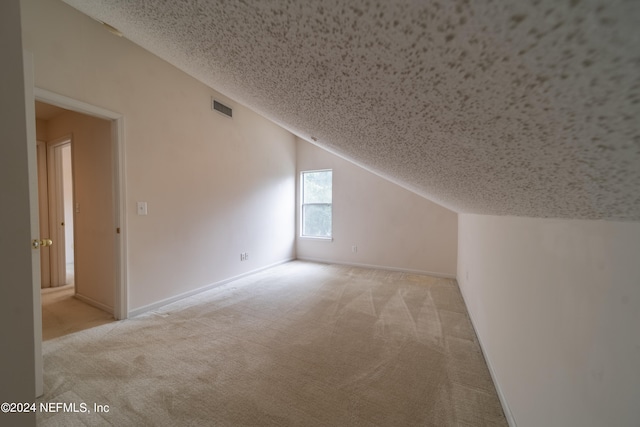 bonus room featuring a textured ceiling, light colored carpet, and vaulted ceiling