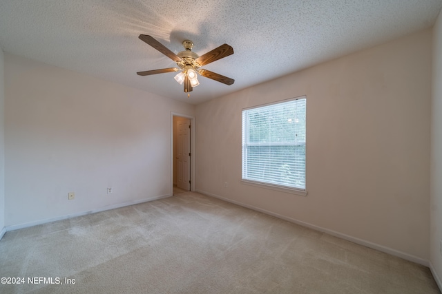 carpeted spare room featuring a textured ceiling and ceiling fan