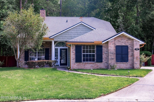ranch-style home featuring a front lawn, a chimney, a shingled roof, and brick siding