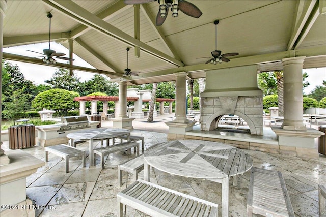 view of patio featuring exterior kitchen, an outdoor stone fireplace, grilling area, exterior bar, and a gazebo