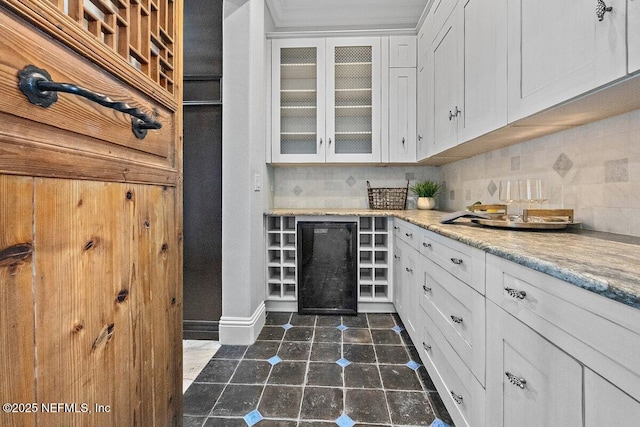 kitchen with decorative backsplash, light stone countertops, and white cabinetry