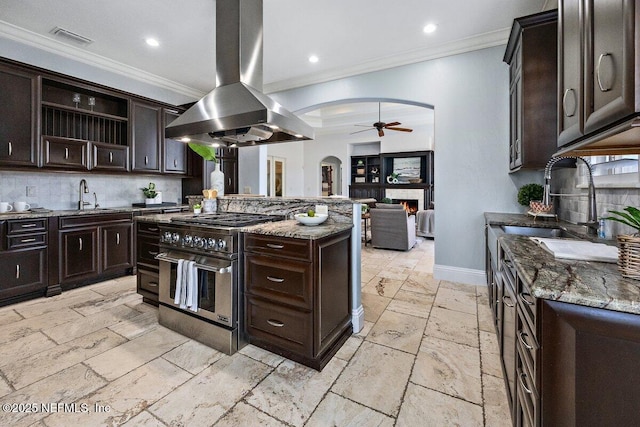 kitchen featuring island exhaust hood, dark brown cabinets, range with two ovens, and sink