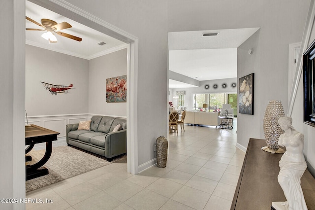 tiled living room with ornamental molding and ceiling fan