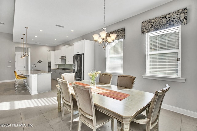 tiled dining space featuring sink and a chandelier