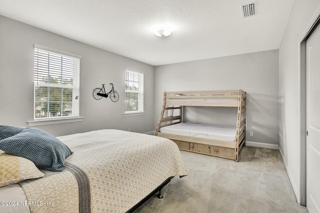 carpeted bedroom with a textured ceiling and a closet