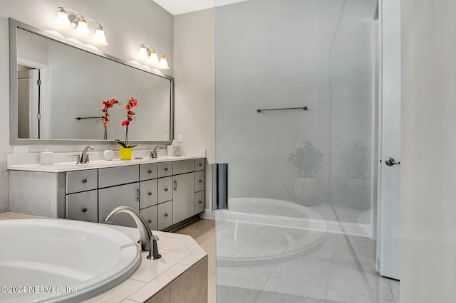 bathroom with vanity, a relaxing tiled tub, and tile patterned flooring