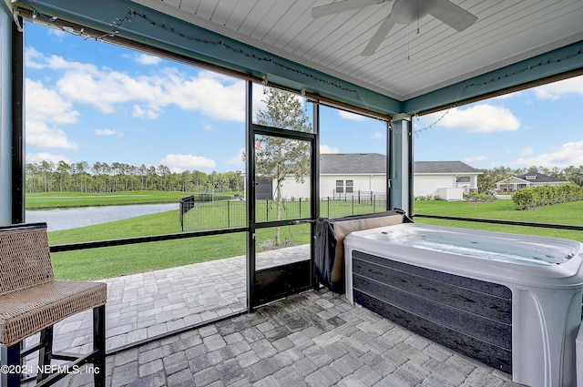 sunroom featuring a jacuzzi, a ceiling fan, and a water view