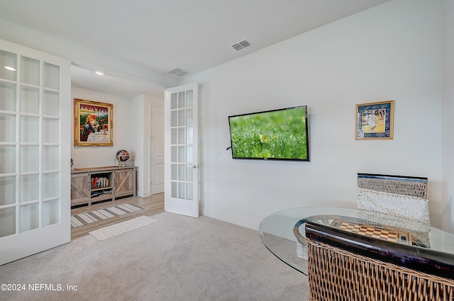 sitting room featuring french doors and light colored carpet