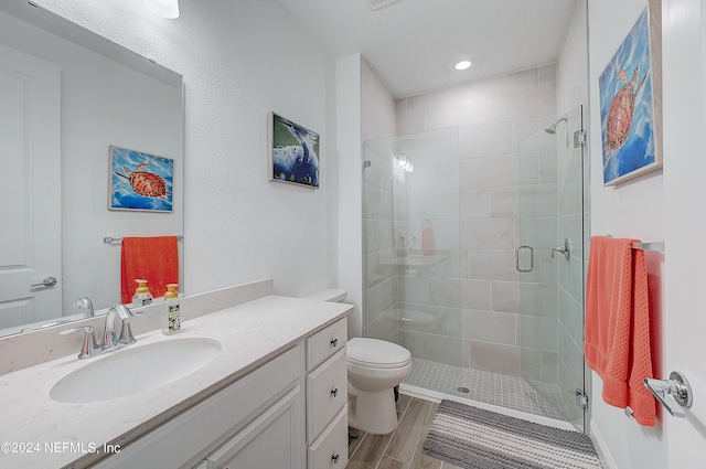 bathroom with vanity, hardwood / wood-style flooring, toilet, and walk in shower