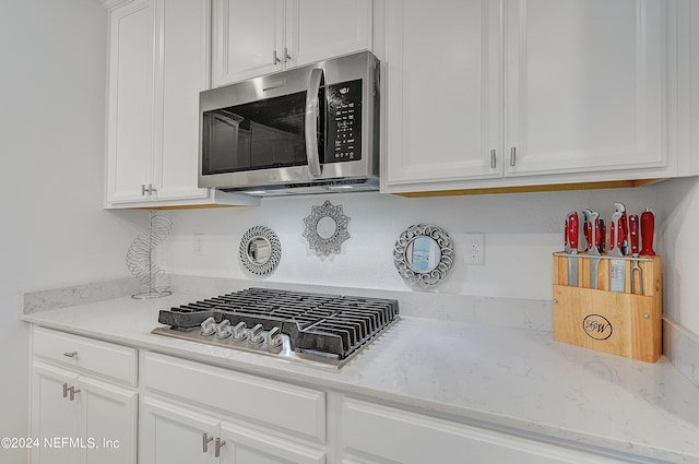 kitchen featuring light stone countertops, appliances with stainless steel finishes, and white cabinets