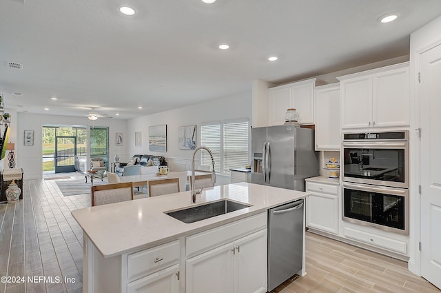 kitchen with appliances with stainless steel finishes, light wood-type flooring, a sink, visible vents, and open floor plan