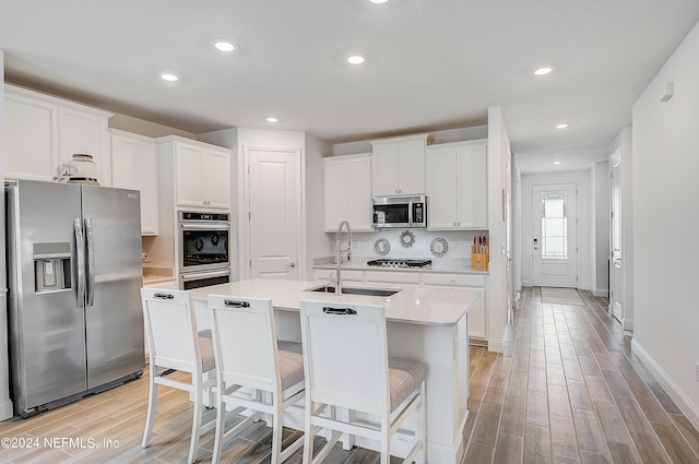 kitchen featuring a center island with sink, sink, white cabinets, and stainless steel appliances