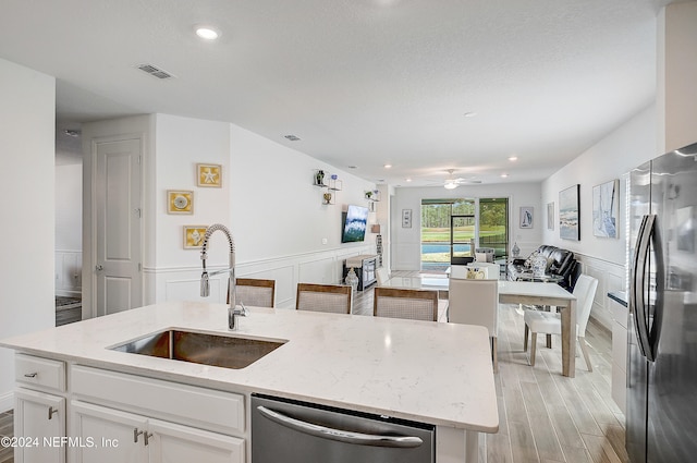 kitchen with sink, white cabinets, light stone counters, and stainless steel appliances