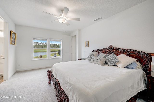 carpeted bedroom featuring ceiling fan, a textured ceiling, and ensuite bathroom