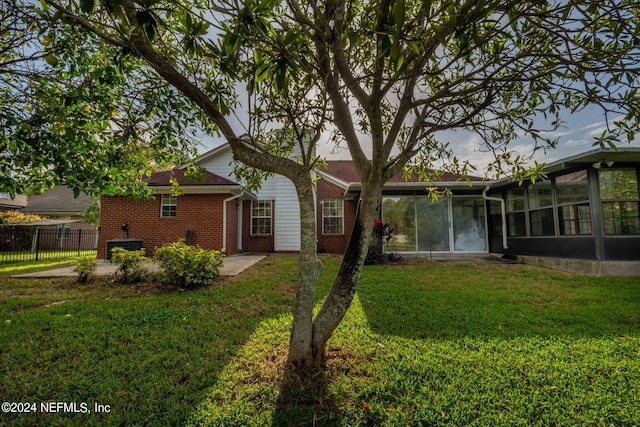 rear view of property featuring a lawn and a sunroom