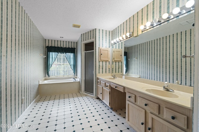 bathroom featuring vanity, a textured ceiling, and shower with separate bathtub