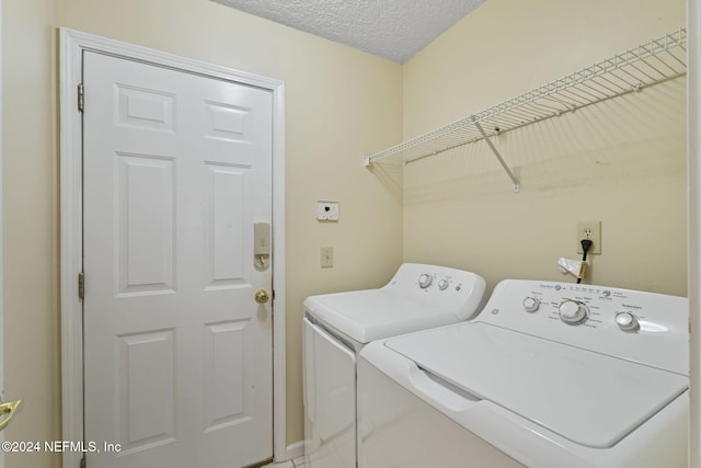 laundry room with a textured ceiling and separate washer and dryer