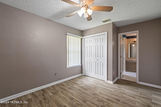 unfurnished bedroom with light hardwood / wood-style floors, a closet, a textured ceiling, and ceiling fan