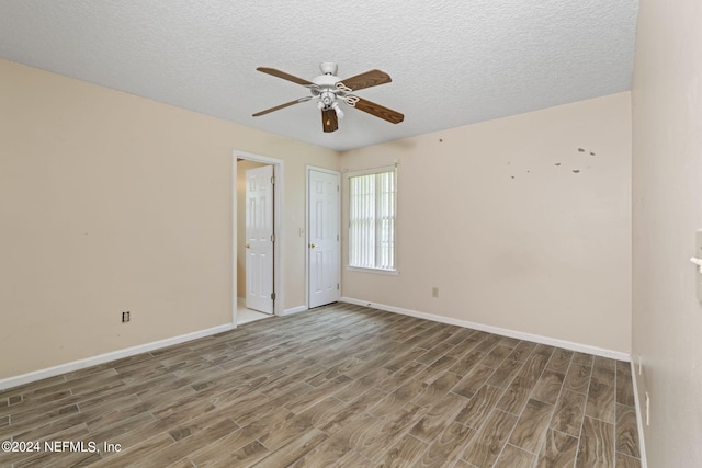 spare room with a textured ceiling, wood-type flooring, and ceiling fan