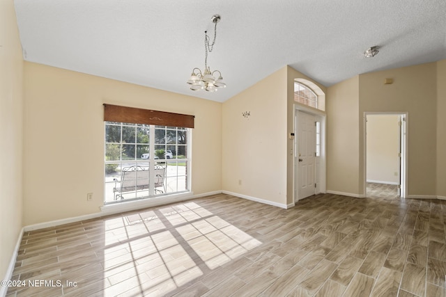 unfurnished room featuring a textured ceiling, a chandelier, and light wood-type flooring