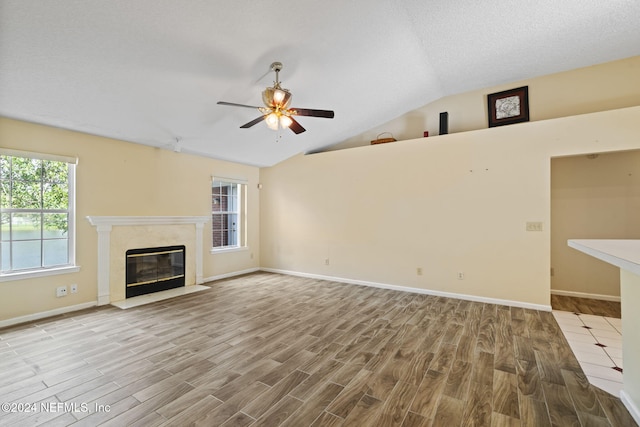 unfurnished living room with ceiling fan, a healthy amount of sunlight, lofted ceiling, and light hardwood / wood-style flooring