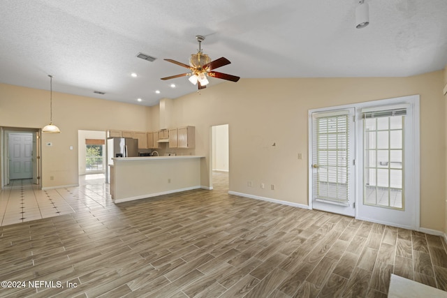 unfurnished living room with light hardwood / wood-style floors, a textured ceiling, ceiling fan, and vaulted ceiling