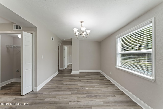 unfurnished dining area with hardwood / wood-style flooring and an inviting chandelier