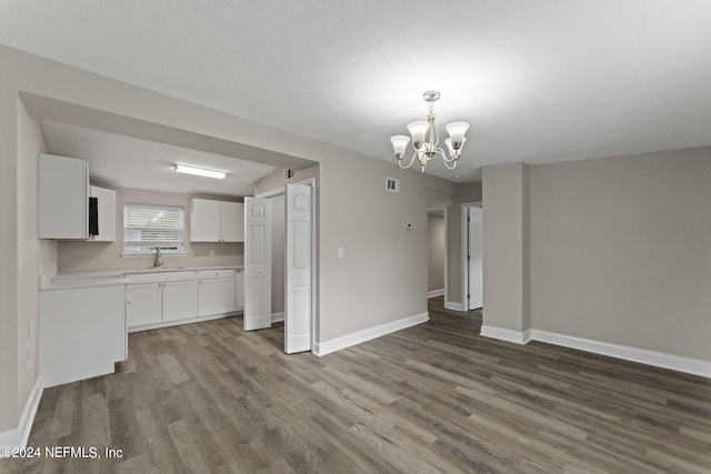 unfurnished dining area with a notable chandelier, sink, and hardwood / wood-style floors