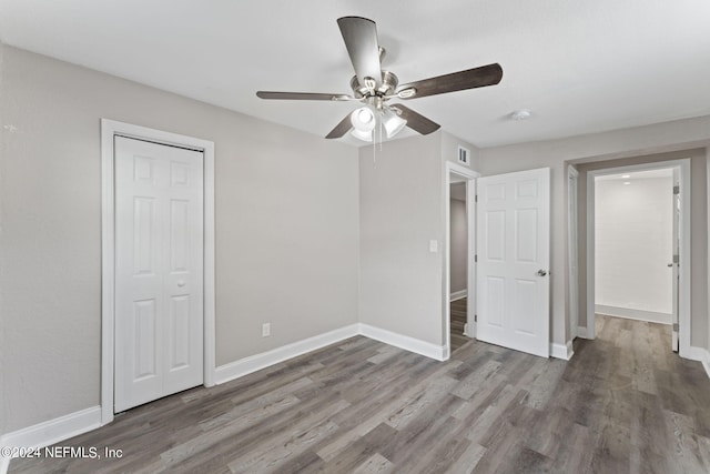 unfurnished bedroom featuring a closet, dark wood-type flooring, and ceiling fan